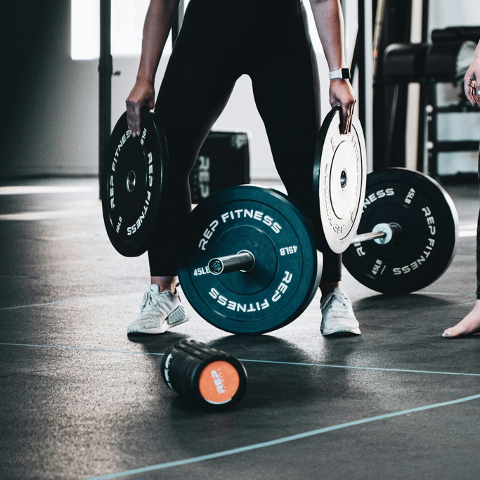 Woman working out at Mojo Fitness Littleton with barbell weights to optimize her weight training workout